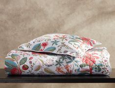 two pillows sitting on top of a wooden table next to a pillow case with floral designs