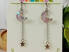 These lovely earrings are perfect for the astrology lover in your life!  Each charm is made from resin dyed in pastel colors with a splash of glitter poured into a tiny metal frame, then the details are hand painted before the whole thing is sealed in a layer of clear resin to protect the mini work of art!    Earrings measure around 2 inches in length with stud findings. Findings are nickel and lead free. Please remove from wearing before swimming or showering. *Note- Hand crafted resin pieces usually have small flaws such as air bubbles. I try to limit these as much as possible and most will be unnoticeable. These flaws won't cause any damage to the piece and are no cause for concern, but they're part of what makes handmade resin pieces unique and one of a kind! Moon Phase Star Earrings For Gift, Whimsical Moon Charm Earrings Gift, Handmade Kawaii Silver Earrings, Silver Dangle Kawaii Jewelry, Handmade Silver Kawaii Earrings, Silver Dangle Earrings In Kawaii Style, Silver Hypoallergenic Kawaii Earrings, Metal Dangle Crystal Earrings With Moon Charm, Hypoallergenic Silver Kawaii Earrings