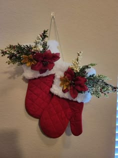 christmas stockings hanging on the wall with flowers and greenery in them, decorated with red velvet mitts