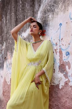 Step into effortless elegance with this full-length draped kaftan adorned with intricate embellishments. This kaftan offers a perfect balance of style and comfort, making it ideal for both casual outings and special occasions. Embrace luxury and grace with this stunning piece that's sure to turn heads wherever you go. Embellished Green Dress For Navratri, Green Tunic Kaftan For Festive Occasions, Bollywood Style Dresses With Draped Sleeves, Anarkali Dresses With Embroidered Neckline, Bollywood Style Dress With Embroidered Neckline For Navratri, Bollywood Dresses With Embroidered Neckline For Navratri, Green V-neck Kaftan For Festive Occasions, Green Kaftan For Wedding And Navratri, Georgette Dress With Cape Sleeves For Navratri