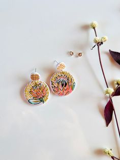 Add a pop of color and playfulness to any outfit with our Handpainted Protea Earrings. These unique earrings feature a fun design on the back and come in two options: with or without black accents. Made with high quality 925 silver stud posts and handcrafted from durable polymer clay. Everyday Hand Painted Pink Earrings, Bold White Jewelry For Gift, Bold White Jewelry For Gifts, Unique Hand Painted Everyday Earrings, Playful Hand Painted Pink Earrings, Unique Hand Painted Earrings For Everyday, Fun Hand Painted Yellow Earrings, Unique Hand Painted Earrings For Everyday Wear, Fun Yellow Hand Painted Earrings