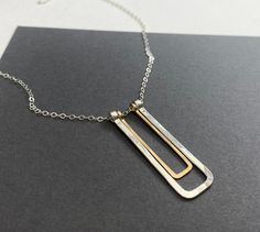 This necklace features a geometric pendant made with heavy gauge sterling silver wire shaped into a narrow rectangle that's been hammered flat with a smaller narrow gold rectangle made from 14k gold filled wire. It hangs on lightweight sterling cable chain and finished with a lobster clasp.  The pendant measures about 1.5" long and about 1/2" wide. Various necklace lengths are available. All jewelry is sent inside a sturdy jewelry gift box. Minimalist Hammered Jewelry With Rectangular Pendant, Minimalist Hammered Rectangular Pendant Jewelry, Minimalist Rectangular Necklace For Everyday Use, Minimalist Rectangular Jewelry For Everyday Use, Minimalist Rectangular Everyday Jewelry, Rectangular Silver Necklaces For Everyday Use, Silver Rectangular Necklace For Everyday, Everyday Silver Rectangular Necklace, Rectangle Pendant Necklace