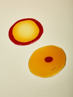 two yellow and red plates sitting on top of a white table next to each other