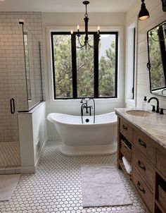 a large white bath tub sitting next to a window in a bathroom with wooden cabinets