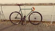 a green bicycle parked on the side of a road next to a body of water