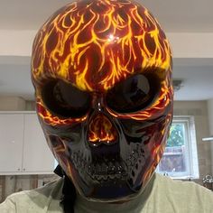 a man wearing a skull mask with flames painted on it