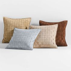 four different colored pillows on a white surface