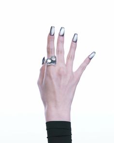 a woman's hand with silver nail polish and ring on her left thumb, against a white background