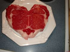 a heart shaped piece of meat sitting on top of a white plate in the shape of a heart