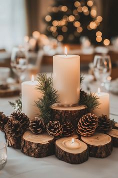 a table topped with candles and pinecones on top of wooden slices covered in greenery