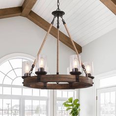 a wooden chandelier hanging from a ceiling in a room with white walls and windows