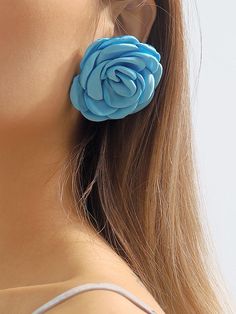 a woman wearing large blue flower earrings