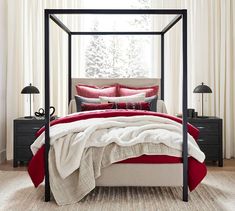 a canopy bed with red and white pillows