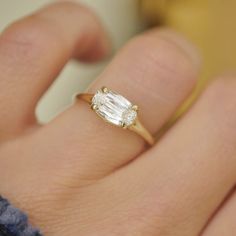 a close up of a person's hand with a diamond ring on their finger