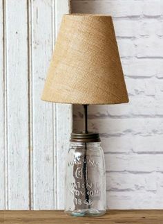 a lamp that is sitting on top of a wooden table next to a brick wall