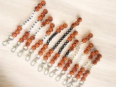 an assortment of orange and black keychains on a white table with keys in them