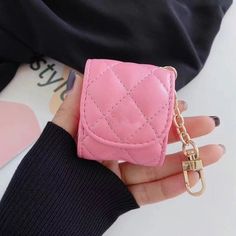 a woman's hand holding a pink wallet with a chain attached to the front