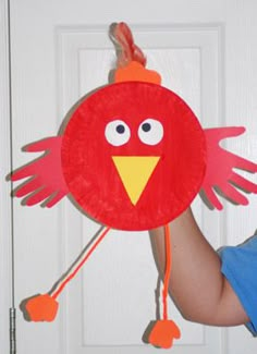 a child holding up a paper plate with a bird on it's head and legs