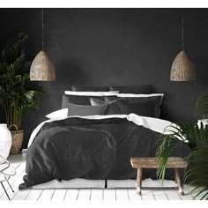 a bedroom with black walls and white flooring, two planters on either side of the bed