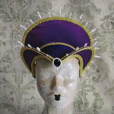 This royal Tudor inspired headdress is covered with silk shantung in either purple (pictured) or black.It is embellished with golden cord trimming all around the edges.It is further trimmed with pearl bead details that create a halo effect. The piece is completed with a beautiful crystal and pearl handmade element at the center front. The base is a headband style, completely handmade to be able to support the shape and design of the headdress. The adjustable elastic, that goes under the hair at Fitted High Crown Costume Hats And Headpieces, Fitted Halloween Costume Headpiece, Fantasy Headpieces For Mardi Gras Costume, Fantasy Costume Headpiece For Mardi Gras, Fantasy Costume Hat For Mardi Gras, Fantasy Mardi Gras Costume Hat, Gothic Fitted Costume Hats And Headpieces, Fantasy Costume Hat With Pinched Crown For Costume Party, Fantasy Costume Headpiece With Pinched Crown