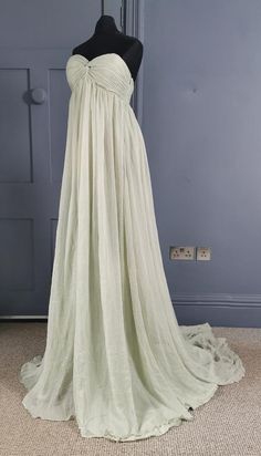 A super elegant evening dress dating to the 1960s, in a diaphanous goddess style. Made in two layers, both stylish seafoam green - underneath a silk like synthetic, sewn with the smooth side to the body, over this a sheer synthetic, lightweight and floating, woven with a fine raised glossy rib. The dress is empire line, the bodice boned, the fabric gathered and twisted at the centre front bust, fastening at the side with an invisible zip. The skirt is in two layers, the top layer longer, flowing Long White Goddess Dress, Empire Waist Medieval Dress, 1960s Inspired Wedding Dress, Empire Line Top, Green Sheer Silk Chiffon Dress, Green Silk Chiffon Maxi Dress, Fantasy Goddess Outfit, Greek Goddess Prom Dress, Flowy Goddess Dress