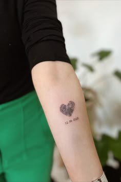 a woman's arm with a small heart tattoo on it