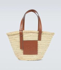 Displaying Loewe's penchant for artisanal design, this basket bag has been crafted in Spain featuring a hand-woven raffia body, tan leather top handles, and an embossed leather Anagram patch..Made in Spain.Material: fabric.Designer color name: Natural/Tan.Internal details: fabric lining.Comes with dust bag.Trim: leather.Adjustable shoulder straps.Closure: open top.Height 24cm-9.5'.Width 43cm-17'.Depth 30cm-12'.Min. length of handles 42cm-16.5'.Max. length of handles 48cm-19' Designer Straw Tote Bag With Handles, Designer Basket Bags With Braided Handles, Designer Basket Bag With Braided Handles, Designer Natural Straw Bag For Daily Use, Designer Natural Woven Straw Bag, Designer Beige Straw Bag With Top Handle, Designer Woven Leather Basket Bag, Designer Basket Bag In Woven Leather, Brown Straw Bag With Intrecciato Weave