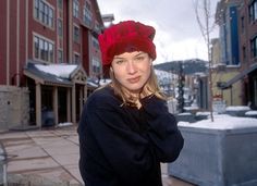 a woman wearing a red hat standing in front of a building on a snowy day