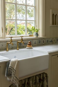 a kitchen sink with two faucets and a window in the backround