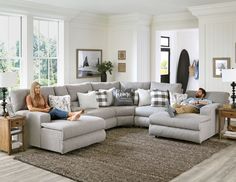 a man and woman sitting on a couch in a large living room with white walls