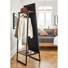 an open clothes rack in a bedroom next to a bed