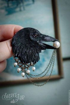 a small black bird with pearls on it's head and chain around its neck