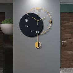 a black and gold clock hanging on the wall in an office area with potted plant