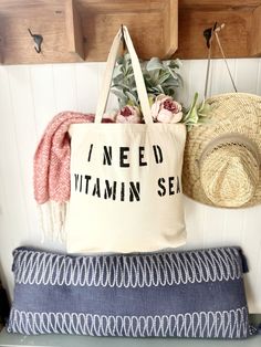 a tote bag sitting on top of a bench next to a hat and flowers