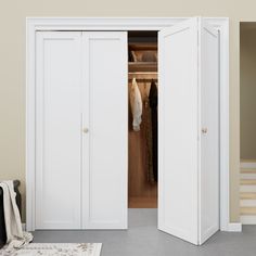 an open closet with clothes hanging on hangers and a rug in the floor next to it