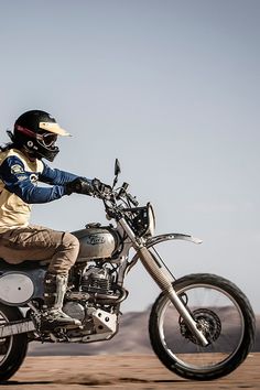 a man riding on the back of a motorcycle down a dirt road