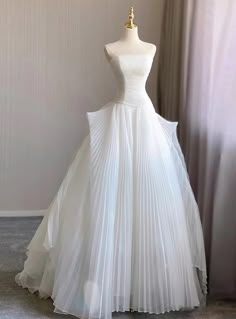 a white wedding dress is displayed on a mannequin headdress in front of a window