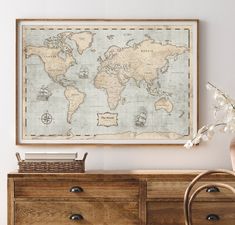 an old world map hangs on the wall above a dresser