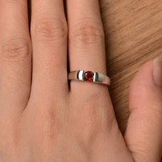 It is a natural garnet ring. The main stone is 5 mm*5 mm round cut.weight about 0.67 carats The basic metal is sterling silver and plated with rhodium. To change the metal to a solid gold (white/rose) or platinum is also available, please ask for a quotation if you want. You can also go to my shop Home for more elegant rings: https://www.etsy.com/shop/godjewelry?ref=hdr_shop_menu Garnet is January birthstone More garnet rings: https://www.etsy.com/shop/godjewelry?ref=seller-platform-mcnav&se Red Solitaire Birthstone Ring With Round Band, Red Solitaire Birthstone Promise Ring, Red Solitaire Birthstone Ring, Sterling Silver Ruby Ring With Round Cut For Promise, Classic Garnet Birthstone Promise Ring, Classic Sterling Silver Birthstone Ring With Tension Setting, Classic Ruby Birthstone Ring For Promise, Silver Birthstone Ring With Ruby, Silver Solitaire Ruby Promise Ring