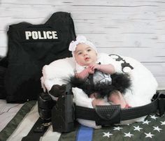 a baby in a police outfit sitting on top of an american flag