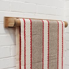 a red and white striped towel hanging on a wooden rack next to a brick wall