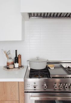 a stove top oven sitting inside of a kitchen next to a counter with utensils on it