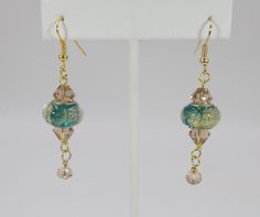 the earrings are hanging from the hooks on the ear wires, and have green glass beads