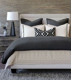 a bed with black and white pillows on top of it next to two nightstands