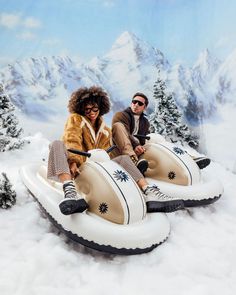 two people sitting on inflatable boats with snow covered mountains behind them