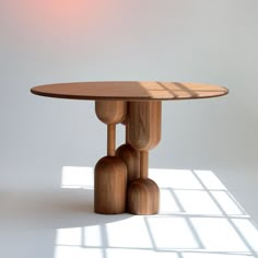 a round wooden table with four legs and three smaller wood balls at the base, against a white background