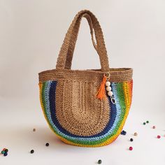 a multicolored straw bag with tassels and beads on the handles, sitting on a white surface