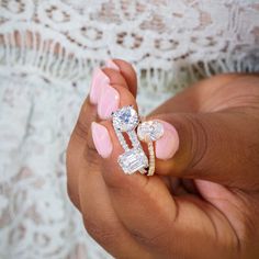 a close up of a person's hand holding an engagement ring and diamond set