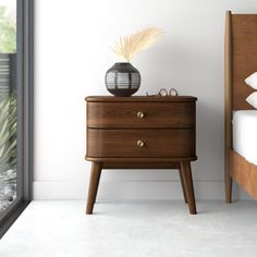 a bed room with a neatly made bed and a night stand next to a window