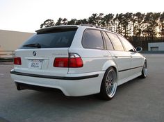 a white bmw is parked in a parking lot